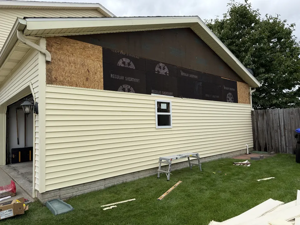 New vinyl siding and a replacement window going up on a garage wall